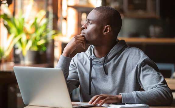 Students looks out window while on laptop